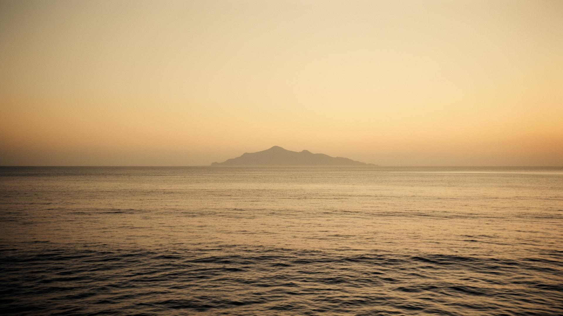 A distant island silhouette on a calm horizon at golden hour